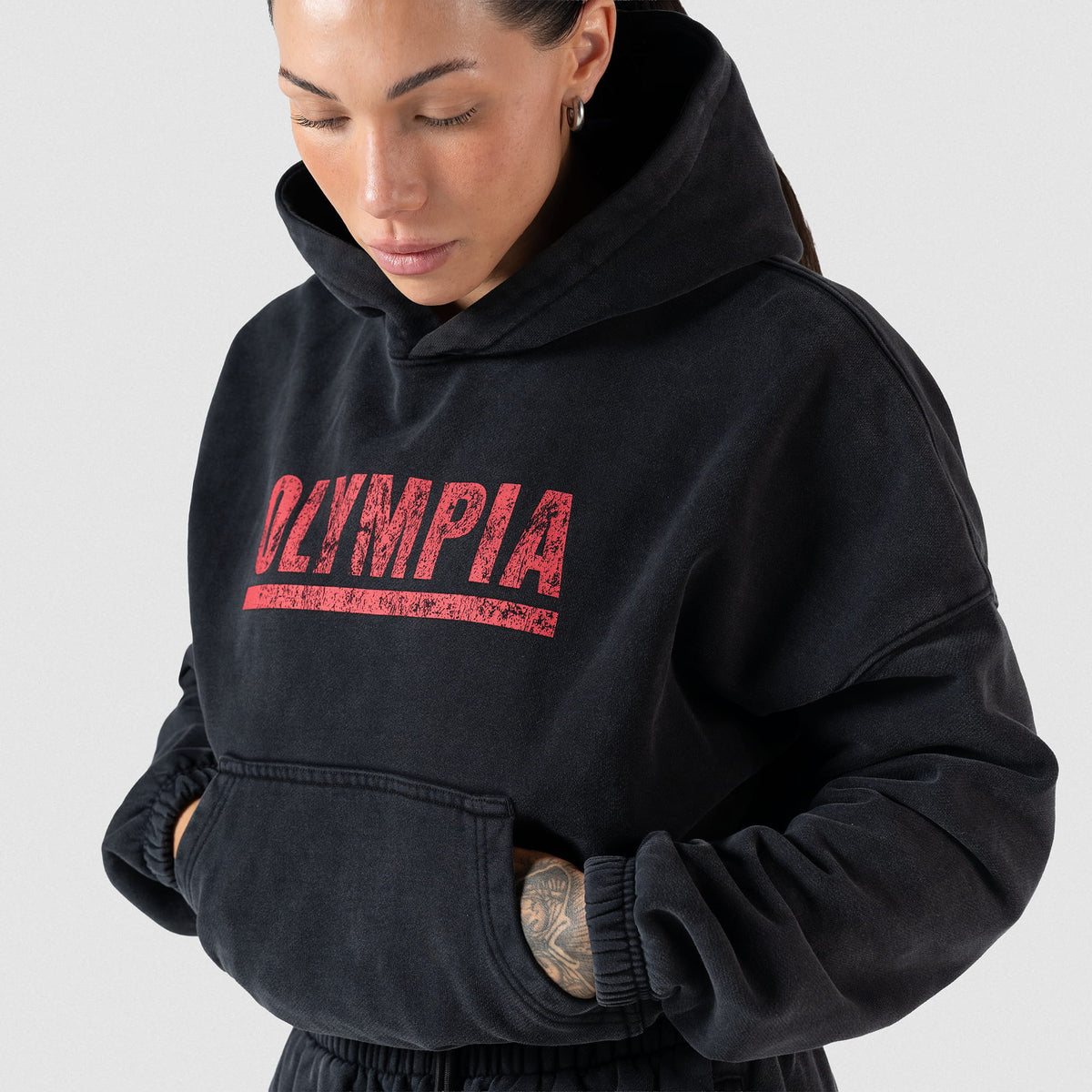 Championship Crop Hoodie | Female model front view while she inserts her hands into the kangaroo pocket of the hoodie
