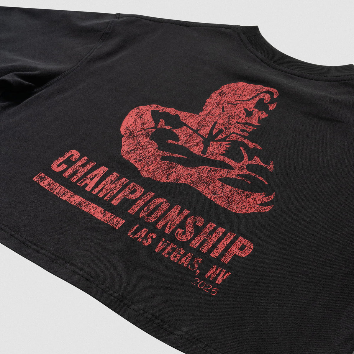 Close up of large front graphic on the women's Championship Crop Tee that has an Olympia red distressed logo and the wordmark "CHAMPIONSHIP LAS VEGAS, NV 2026" below it