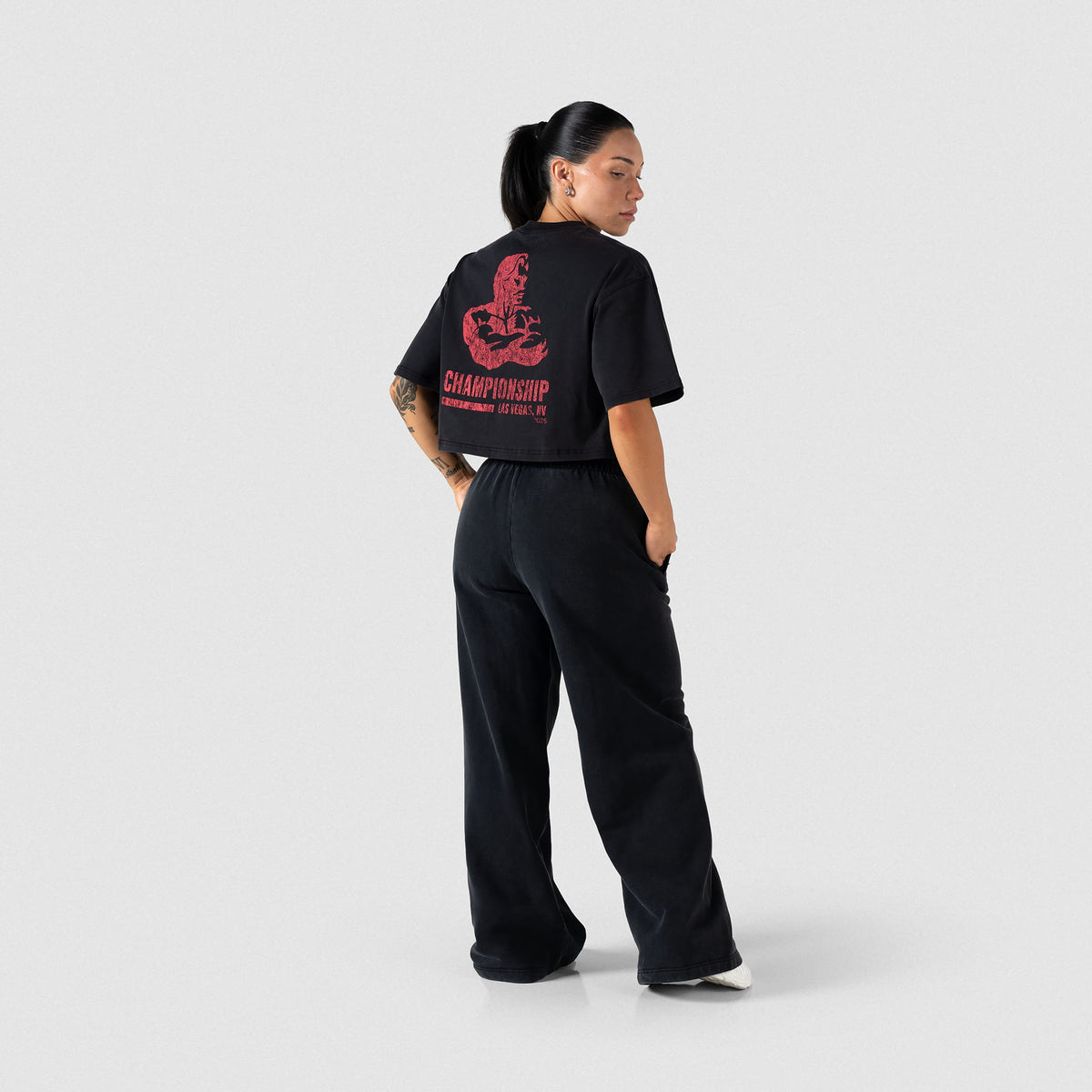 Back full body view of model pairing the Championship Crop Tee with black sweatpants