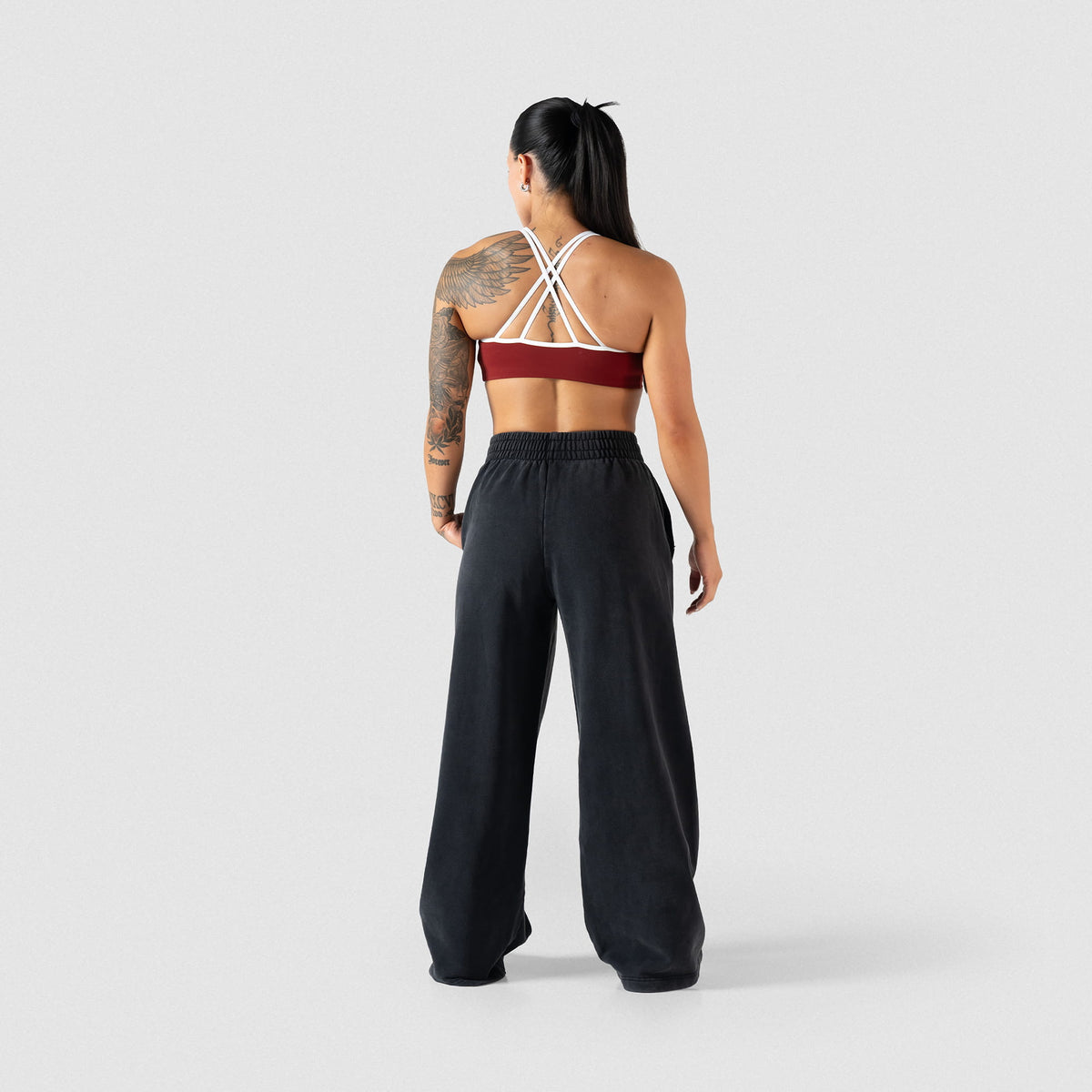 Back of the Olympia High Neck Bra with red/white contrasting details, paired with black sweatpants