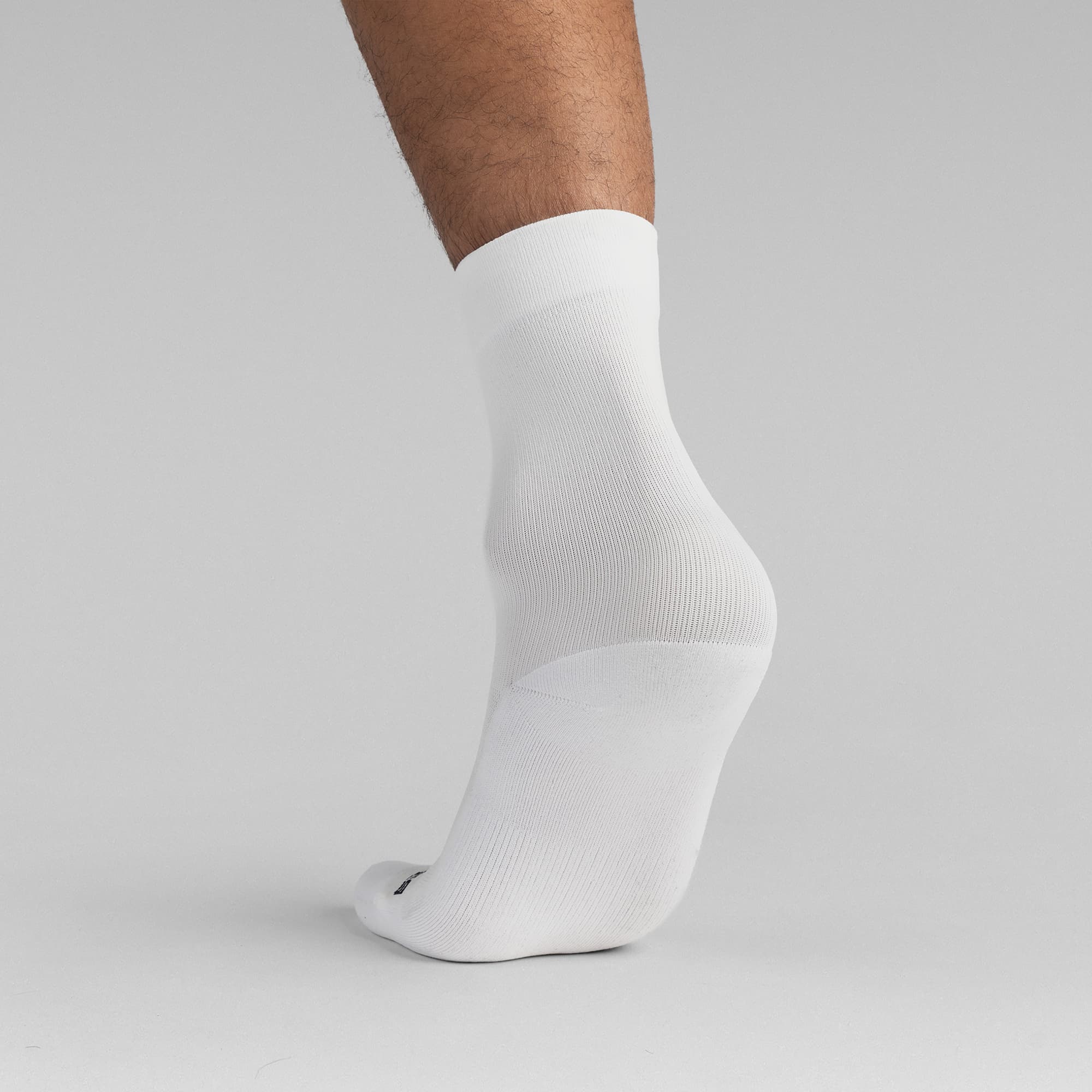 Athlete wearing the White Stryda™ Crew Run Socks back view taking step
