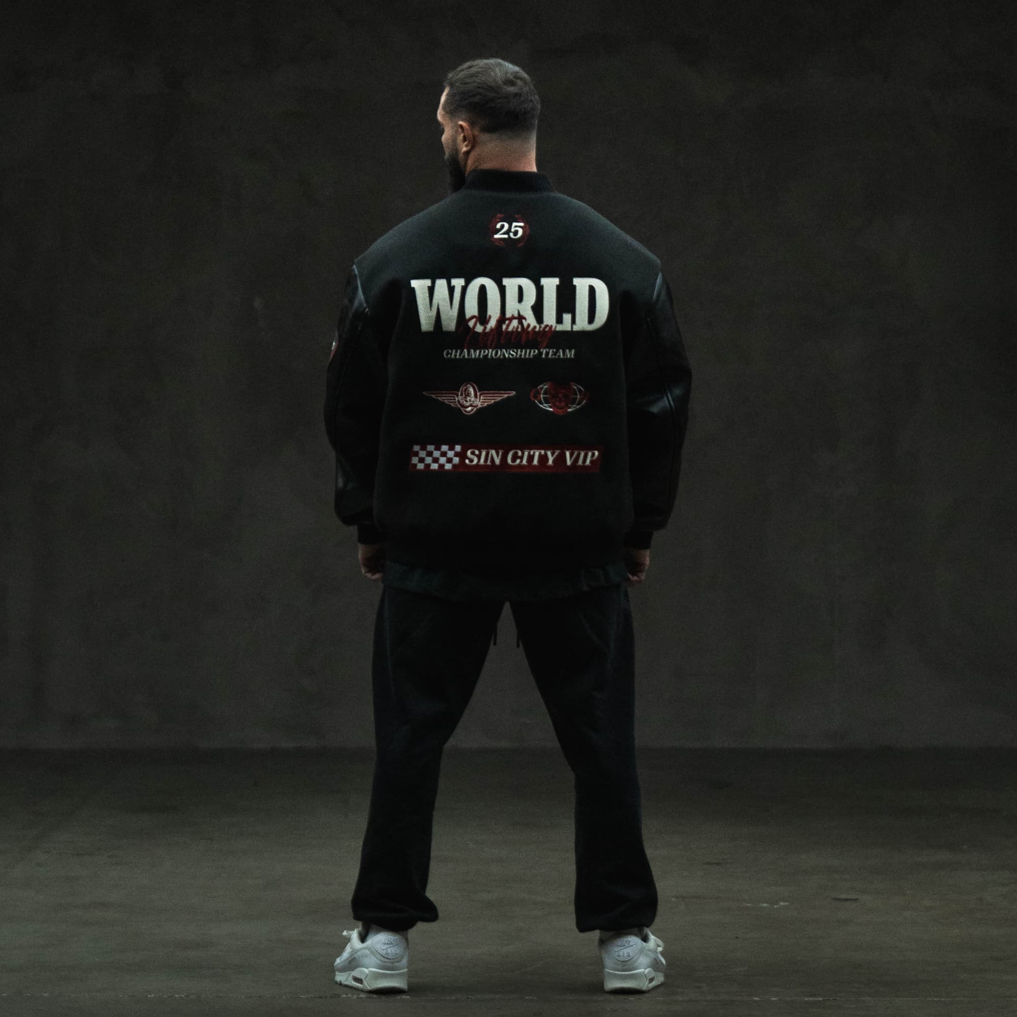 Model full-body back view wearing the Racing Team Varsity Jacket with bold graphics.