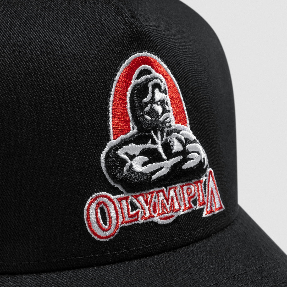 Close up of the front logo on the Signature 5-Panel Trucker Hat of the Classic red and black Olympia Bodybuilding Logo