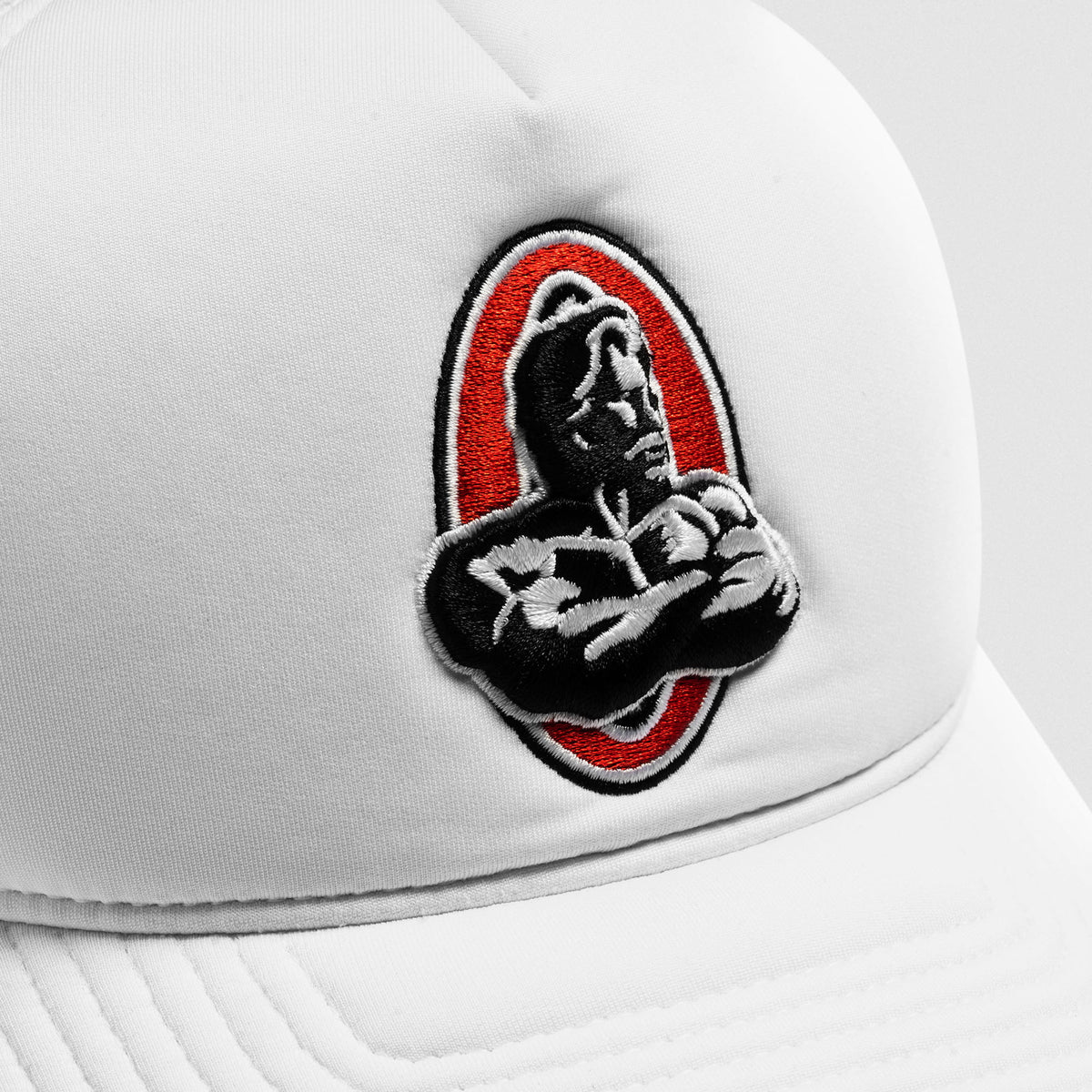 Close up view of the Red, Black, and white Classic Olympia Signature bodybuilding logo on the Signature Foam Trucker Hat