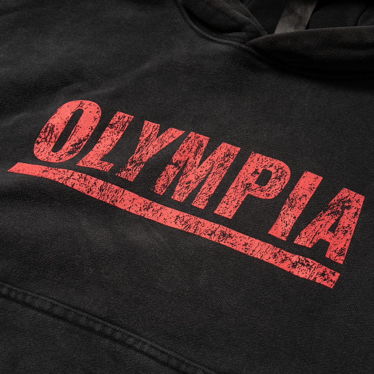 Championship Crop Hoodie | Close up feature of front "Olympia" underlined logo in red against black fabric
