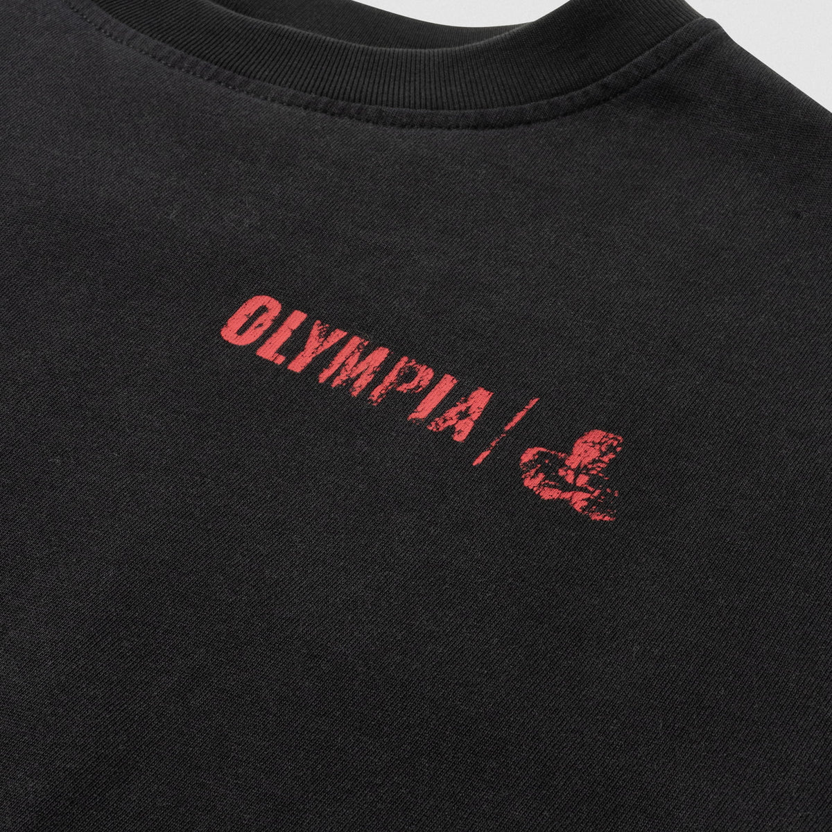 Close up of small distressed front graphic in red font that says "OLYMPIA" and then has the Olympia logo