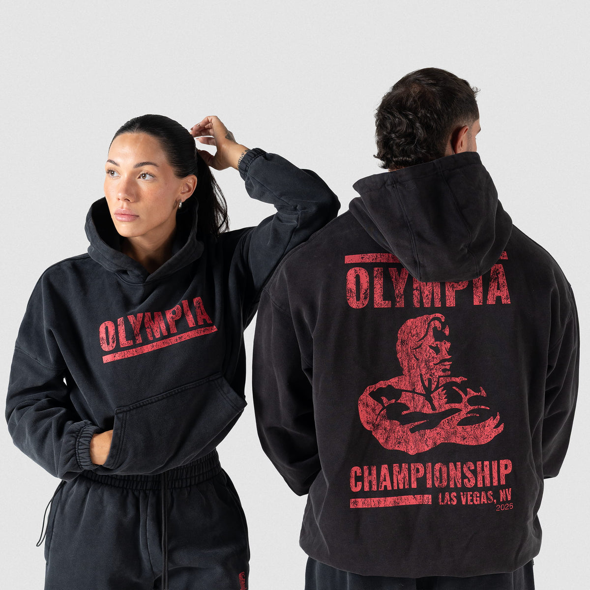 Championship Hoodie | Female model wearing the cropped version of this hoodie, towards the camera, while male model wears the men's version away from the camera to showcase both logos