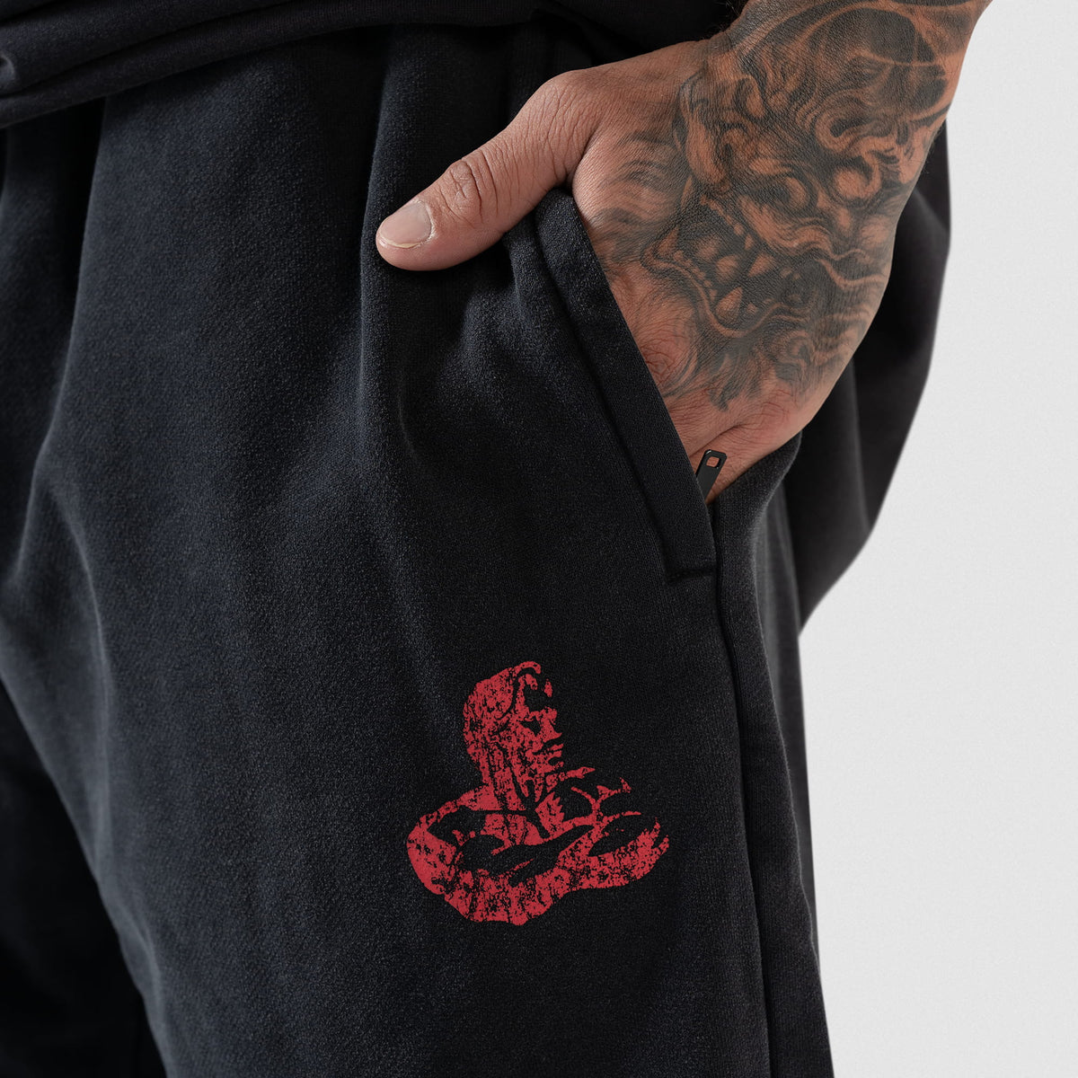 Close up view of distressed red Olympia logo below an opened zippered side pocket that has a hand inside