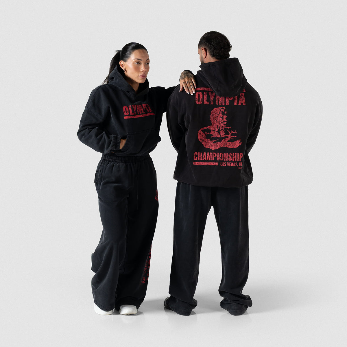 Female model wearing the Championship Wide-Leg Jogger black sweatpants, next to a male model wearing the male version