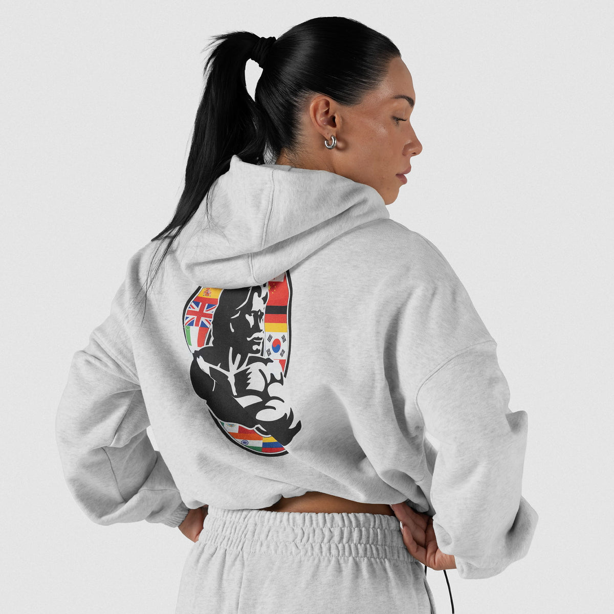International Division Crop Hoodie | Model back view of the gray pullover hoodie, showcasing the large International Division Olympia logo on the back