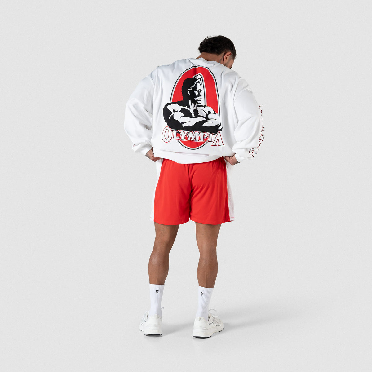 Full body back view of the Signature Long Sleeve in white as male model holds the ends of the shirt