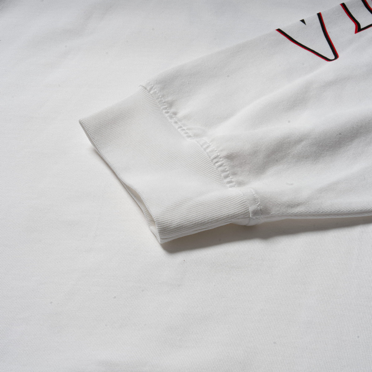 Close up view of the Signature Long Sleeve Tee in white showing the cuffed sleeves