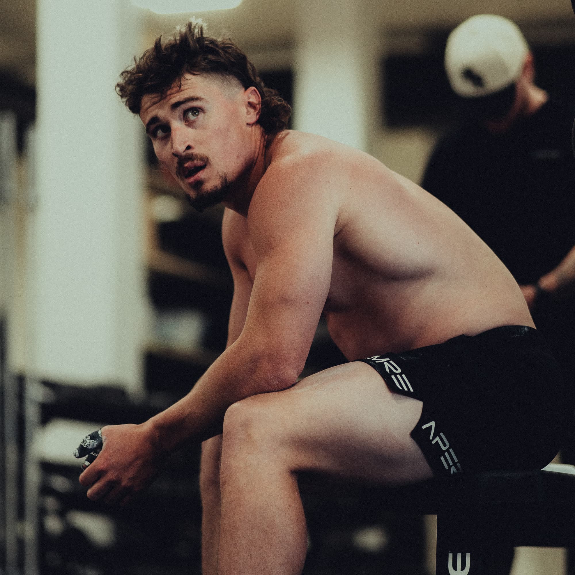 Justin Medeiros resting on a bench in the gym after a workout.