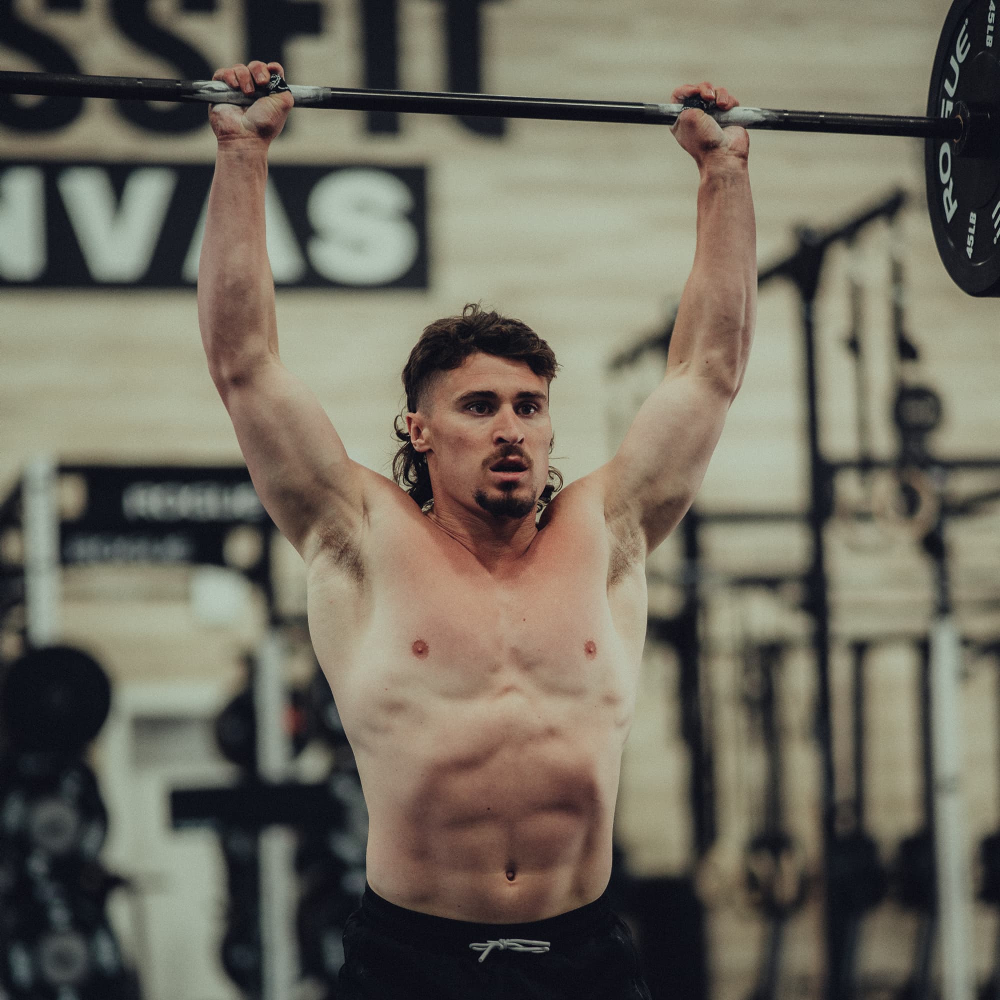 Justin Medeiros lifting a barbell overhead during training.