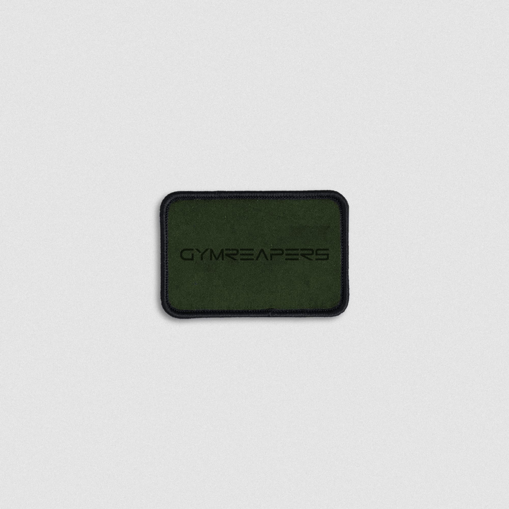 Rectangular green fabric patch with black embroidered Gymreapers logo and black stitched border.