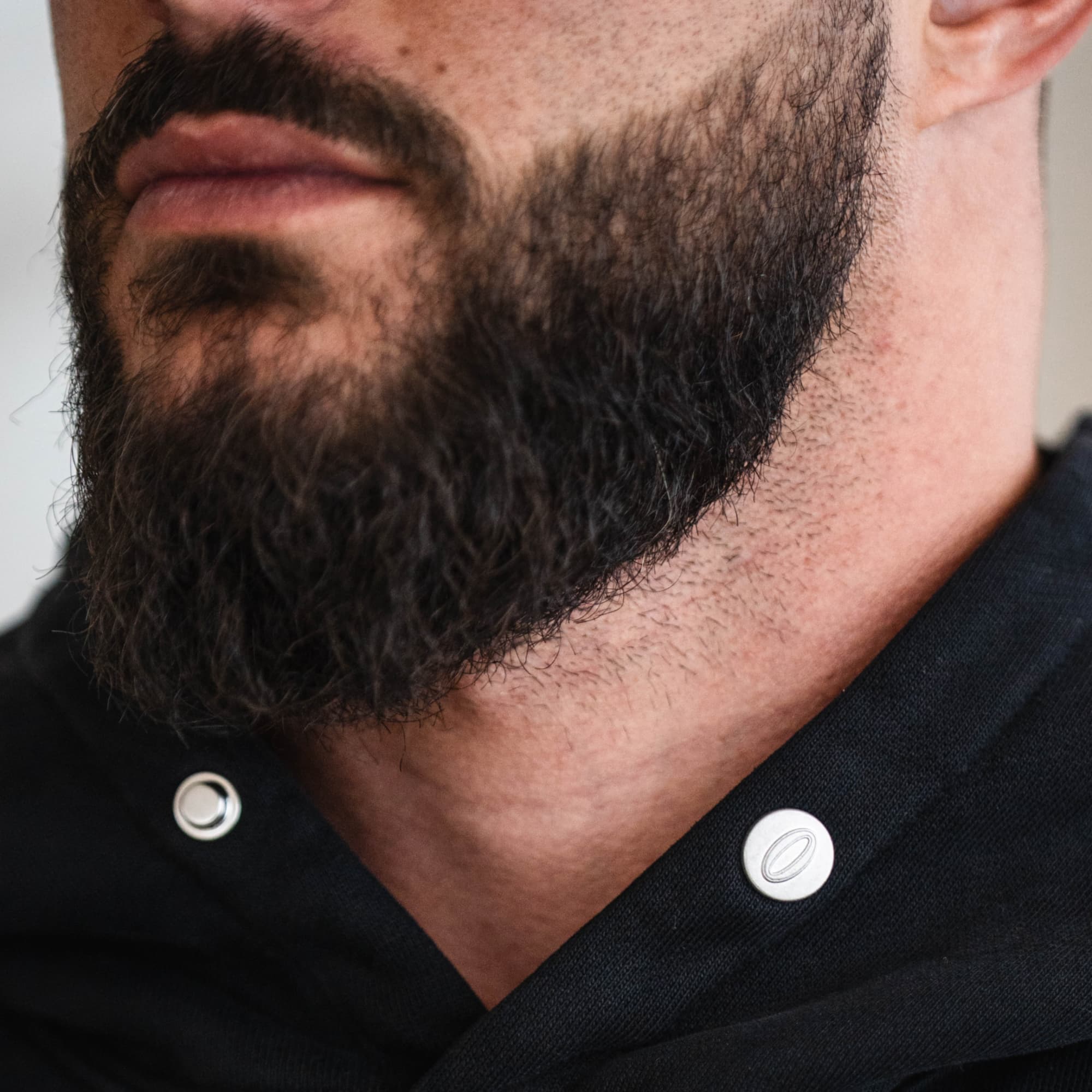 Close-up of the Olympia Hoodies custom Olympia logo buttons, shown on male athlete.