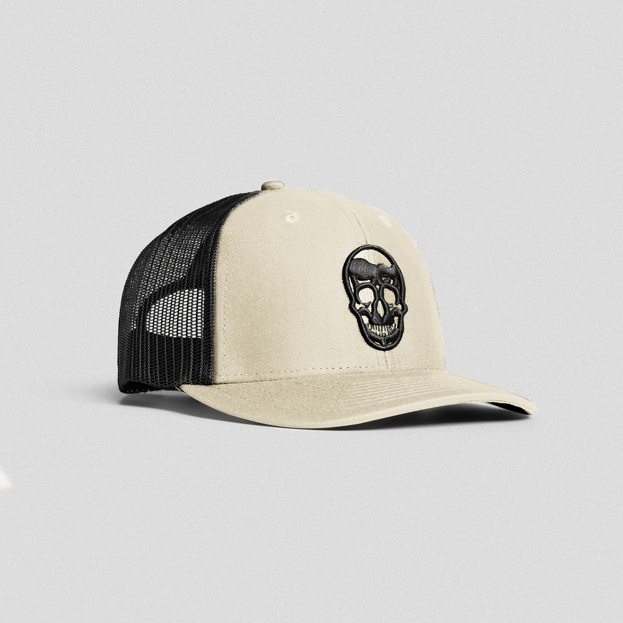 Front view of Gymreapers sandstone trucker hat with embroidered skull logo