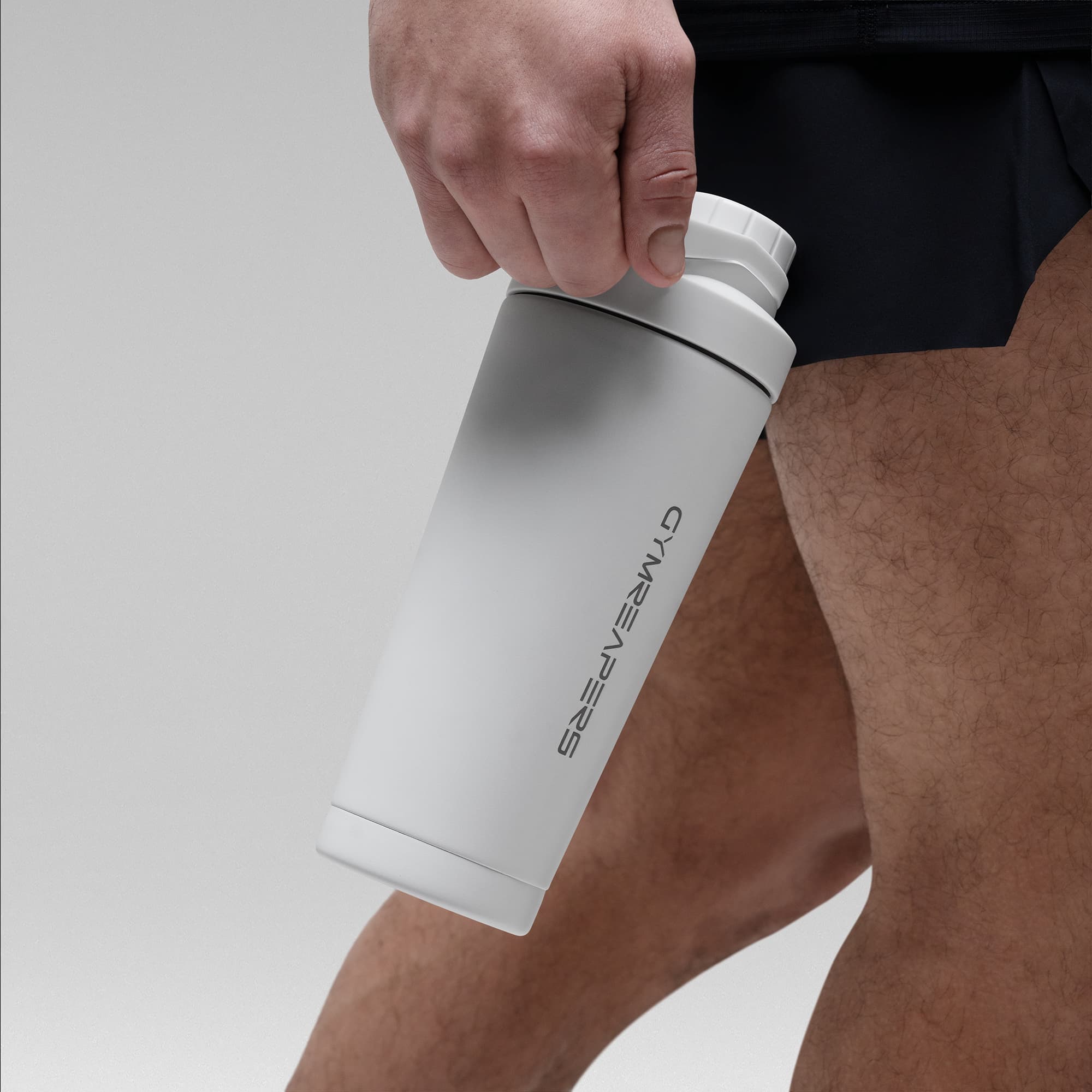 Athlete holding the White Stainless Steel Shaker by the built in carry loop showcasing Gymreapers logo